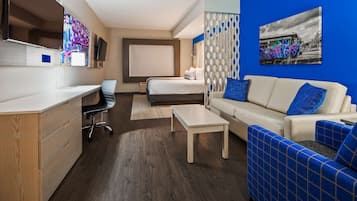 Una moderna camera d'albergo con un letto, un divano, una scrivania e una televisione.