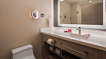 Un baño moderno con un lavamanos blanco, un espejo grande y un inodoro.
