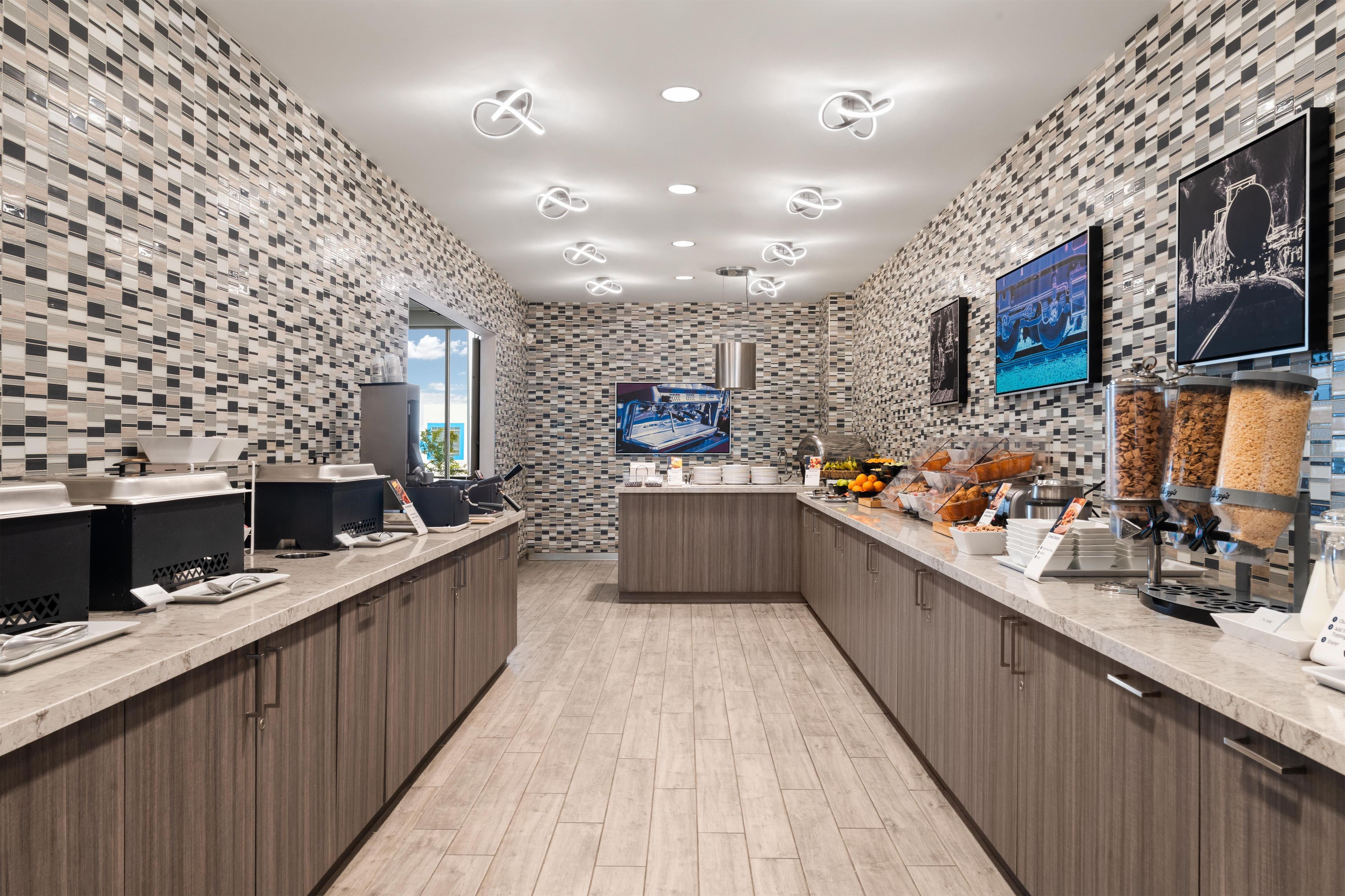 Una cocina moderna con un respaldo de azulejos a cuadros, una isla central y una zona de bufé con dispensadores de alimentos.