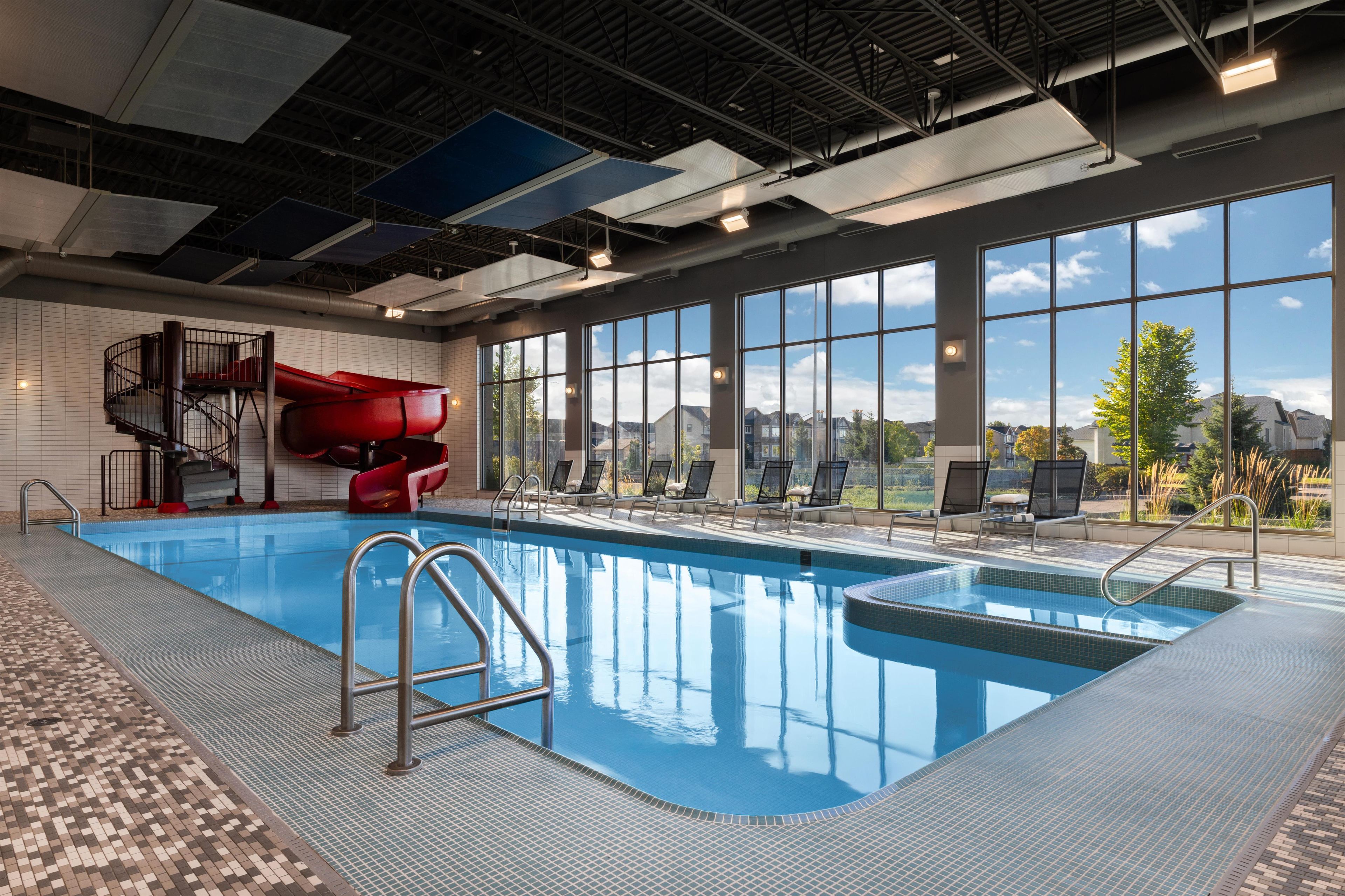 Piscina interior con tobogán, ventanas amplias y vistas al exterior.