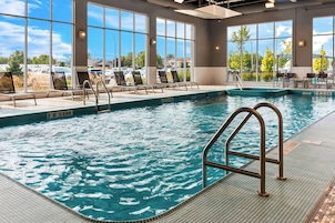 Una piscina interior con agua cristalina, un trampolín y sillas de descanso.