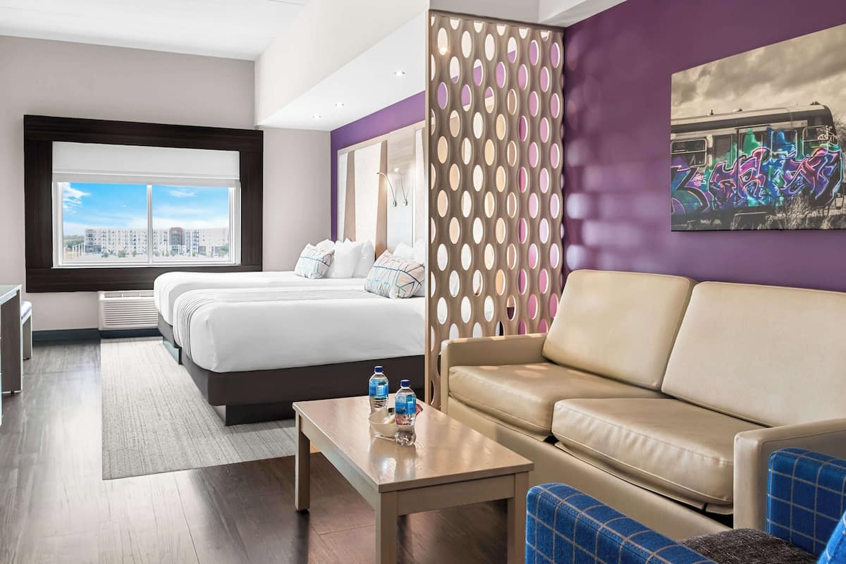 Ein Hotelzimmer mit Bett, Sofa, Couchtisch und Blick auf die Stadt.