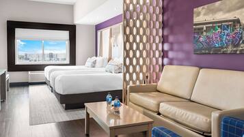 Una habitación de hotel con cama, sofá, mesa de centro y vistas a la ciudad.