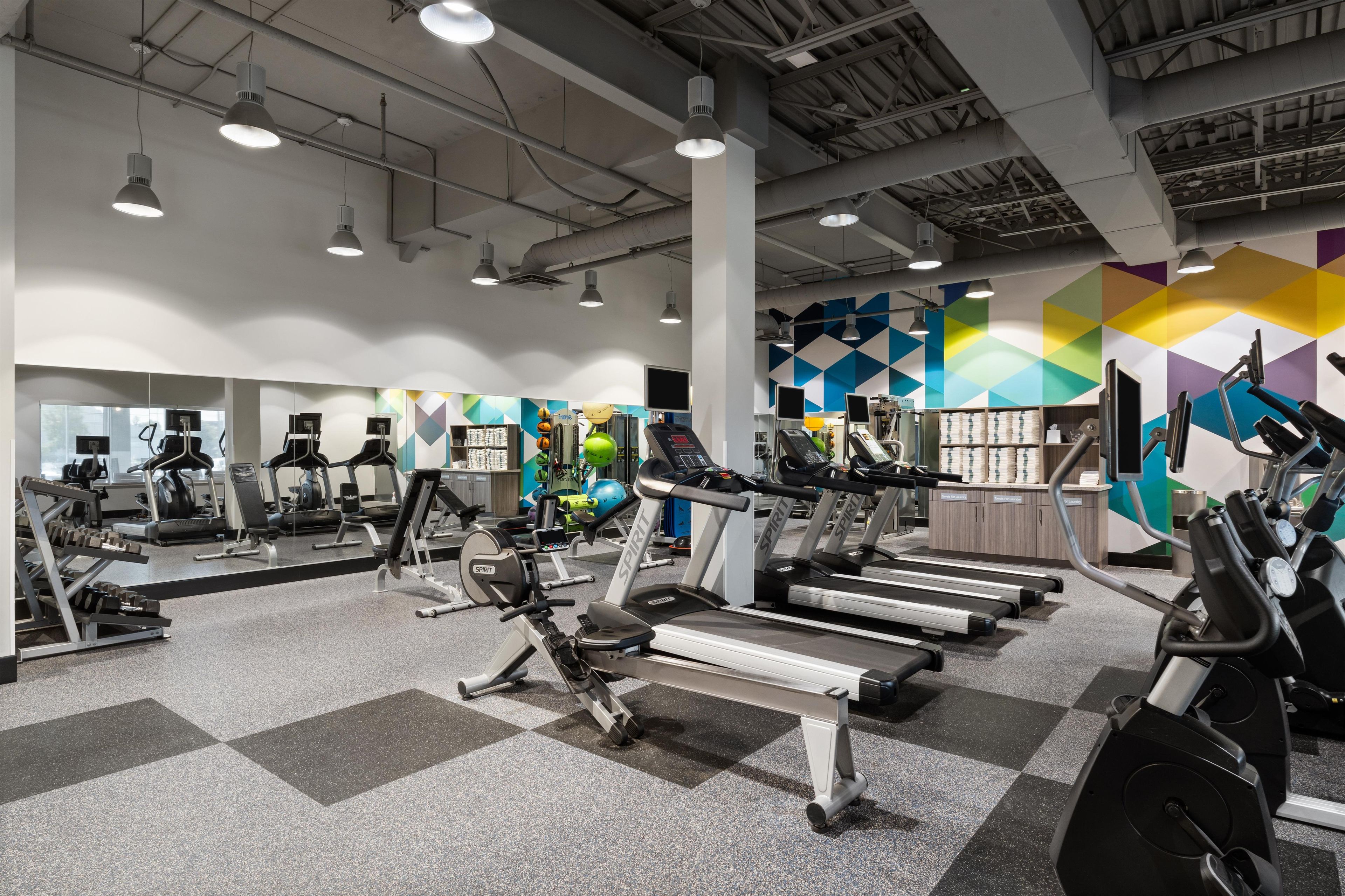 Une salle de sport équipée de plusieurs tapis de course, de vélos d’appartement et d’appareils de musculation.