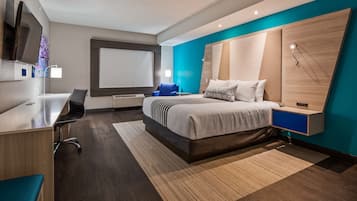 Una habitación de hotel moderna con una cama grande, un escritorio, una silla y un televisor.