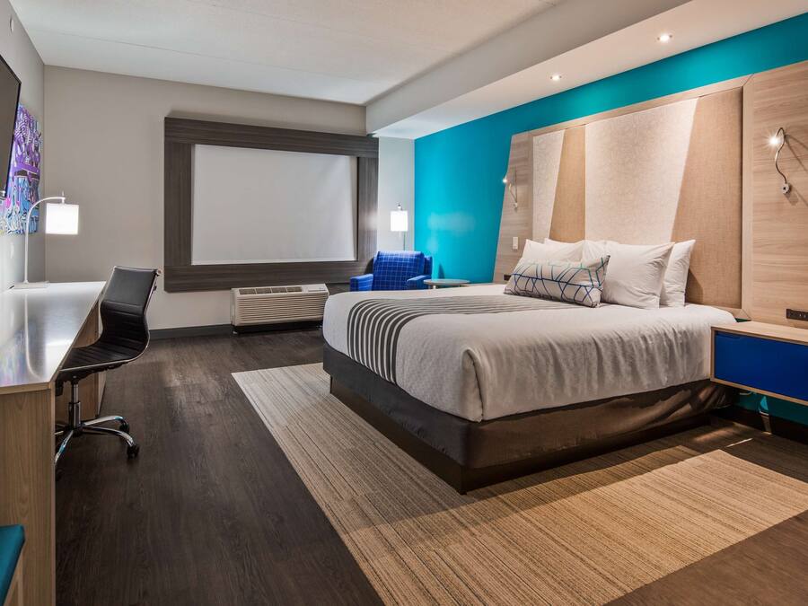 Una habitación de hotel moderna con una cama grande, un escritorio, una silla y un televisor.