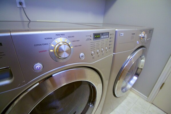 A front view of a front-loading washing machine with control panel, buttons, and a digital display. - Spacious, 4BR Single-Level near Parks (Beaverton)
