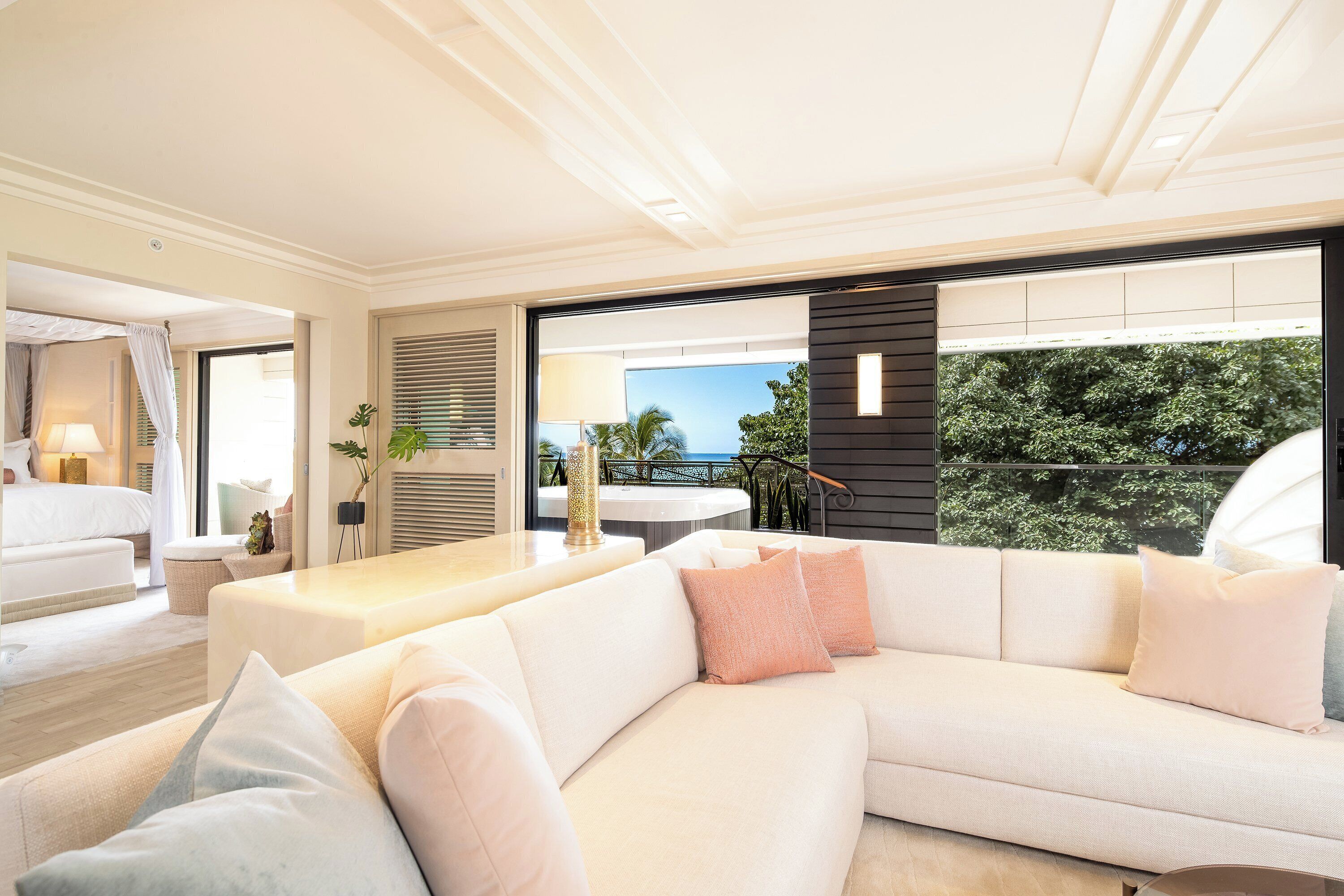 A modern living room with a white sofa, a coffee table, and a view of the outdoors.