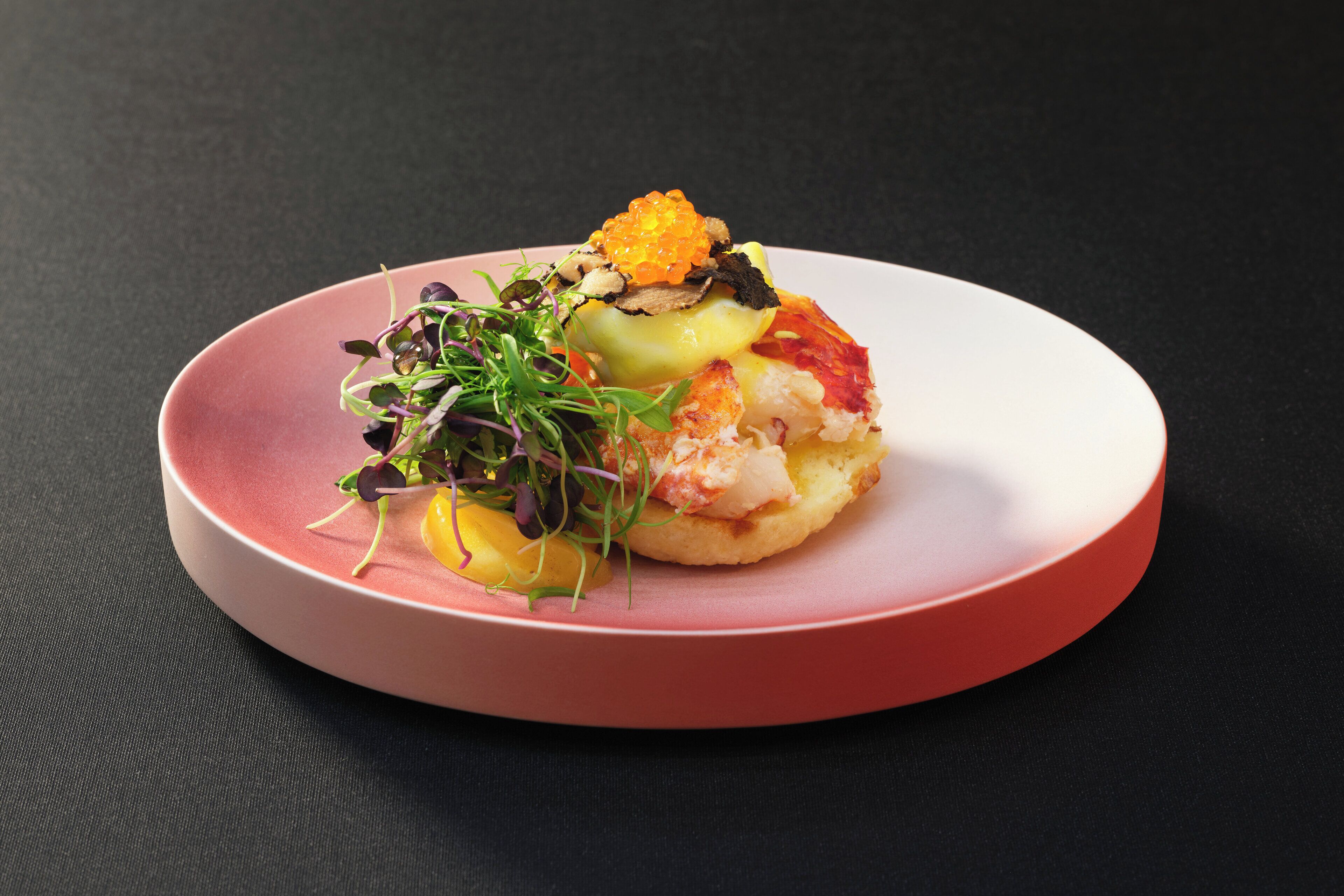 A plate with a variety of food items, including seafood and greens, on a dark background.