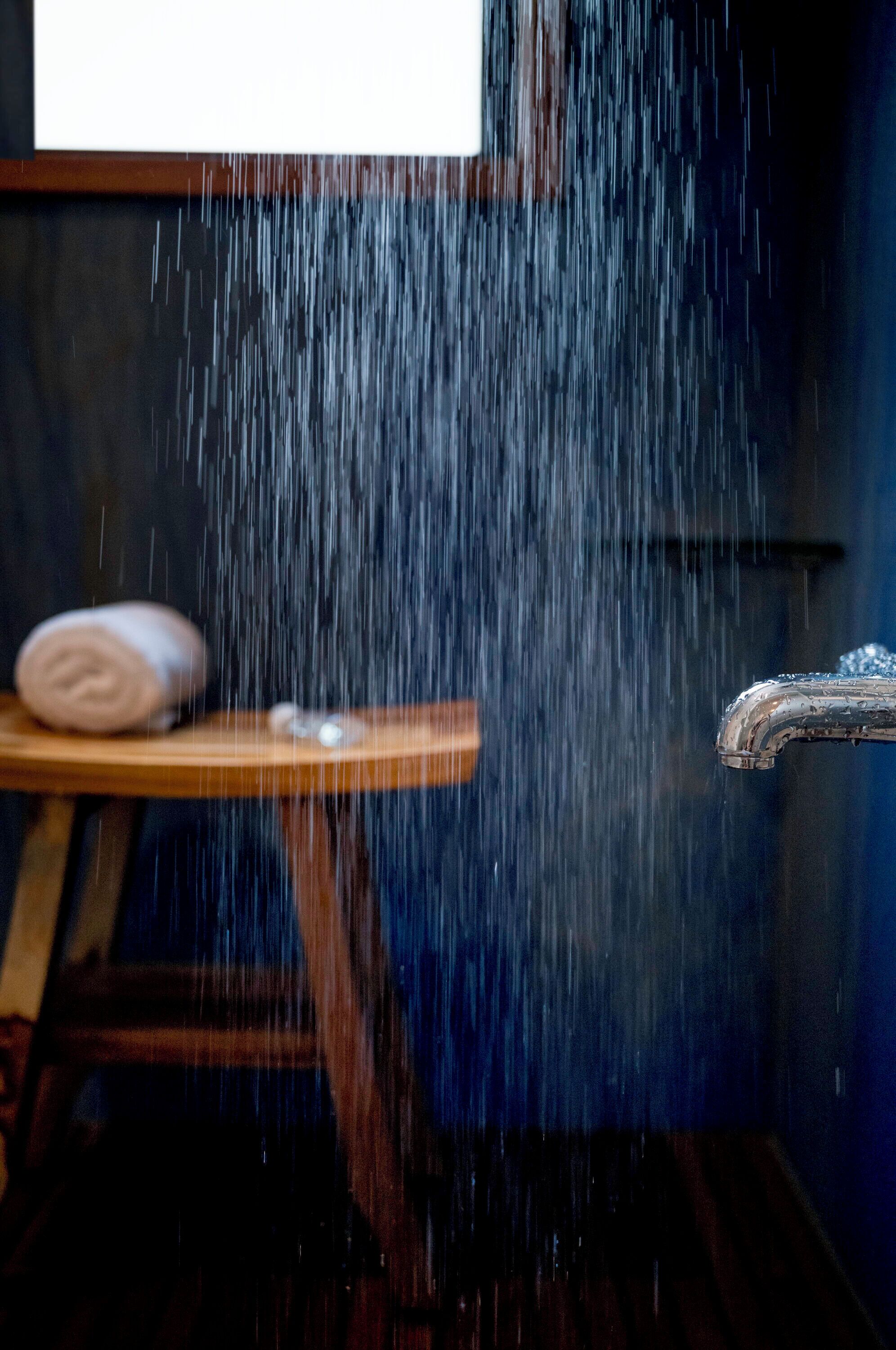 A shower with a wooden shelf holding a rolled towel.