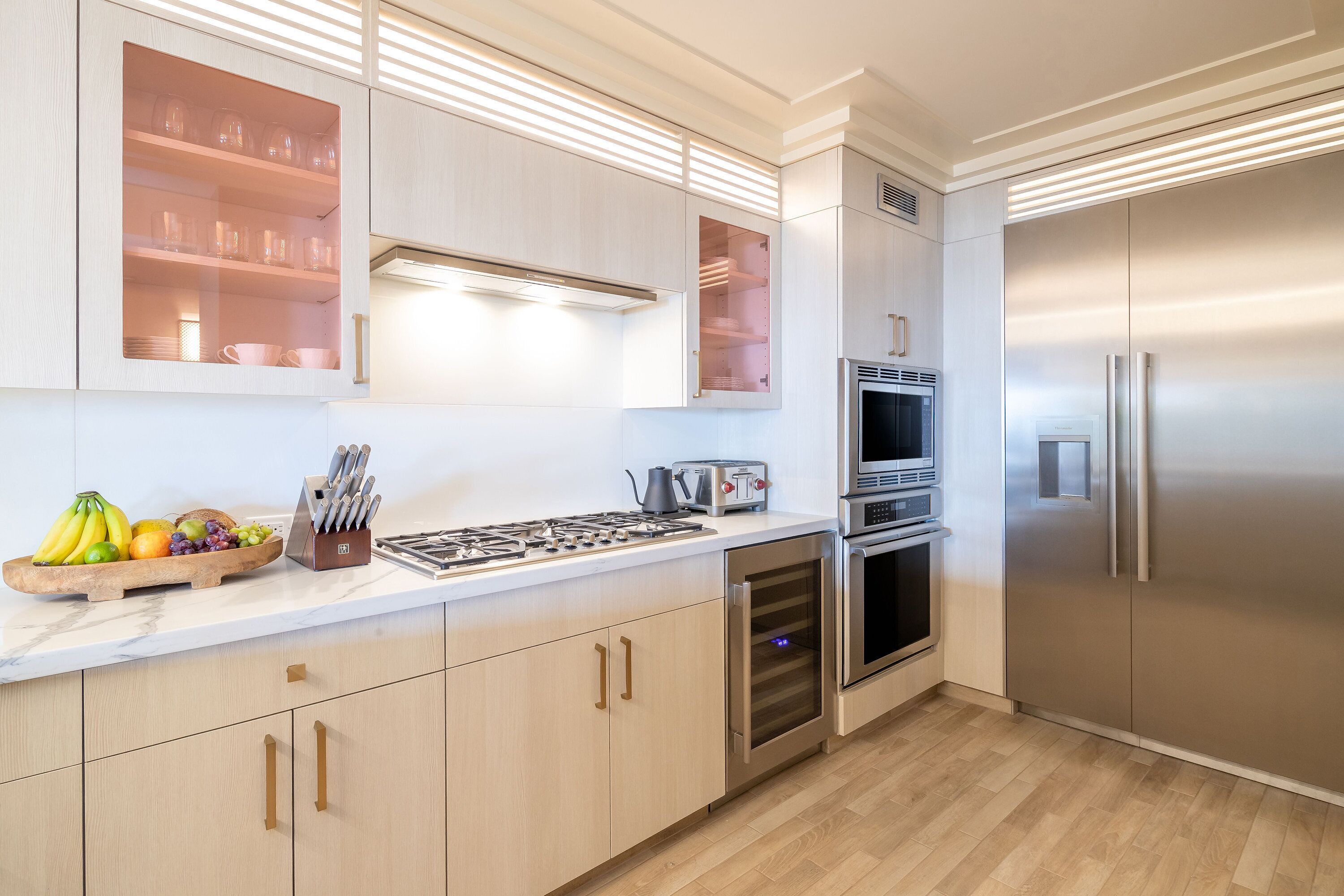 A modern kitchen with stainless steel appliances, wooden cabinets, and a marble countertop.