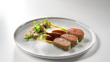 A plate with three pieces of meat, a sauce, and some greens.