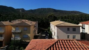 A residential area with terracotta-tiled roofs, multi-story buildings, and a mountainous backdrop. - Habitacions Can Pau Guest House (Llanca)