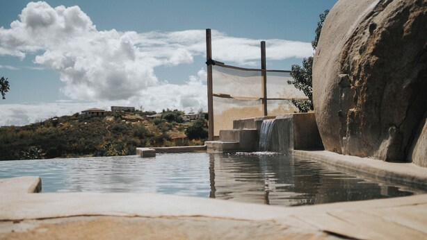 Ein Pool mit Wasserfall, Steintreppe und einem großen Felsen.