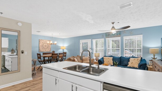 A modern kitchen with a central island, white cabinetry, and a built-in dishwasher. - Peachtree Place By Panhandle Getaways (Panama City Beach)