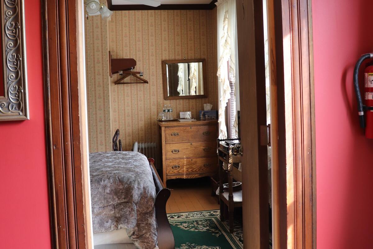 A room with a bed, dresser, and a mirror.