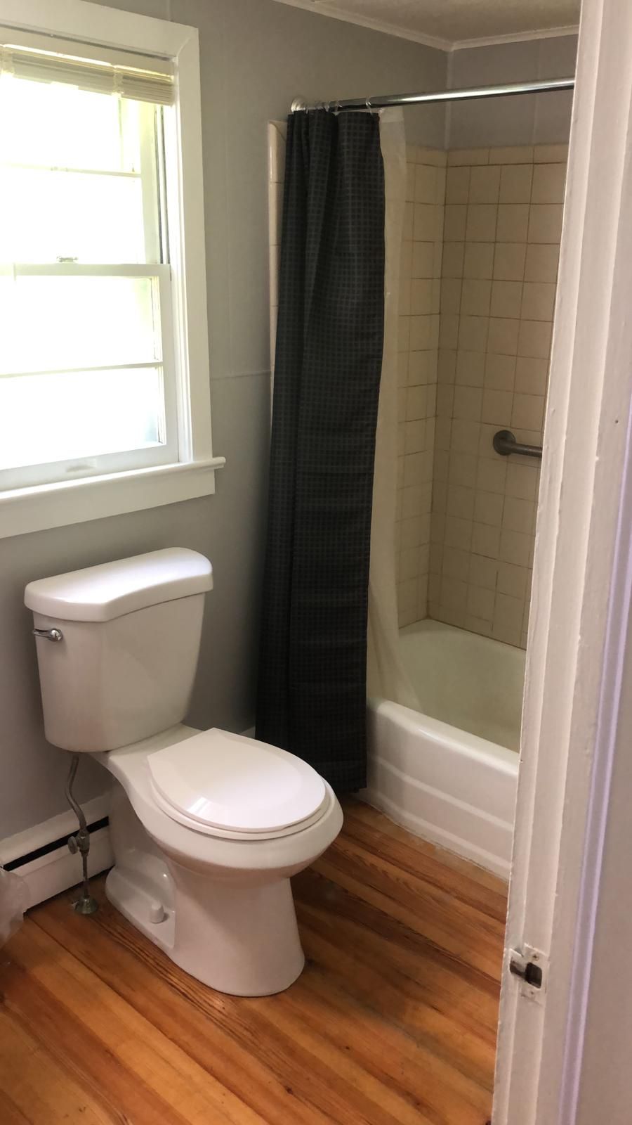 Une salle de bain avec des toilettes, une douche et une fenêtre.