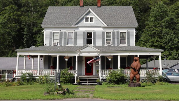 A two-story house with a porch, a front door, and a chimney.