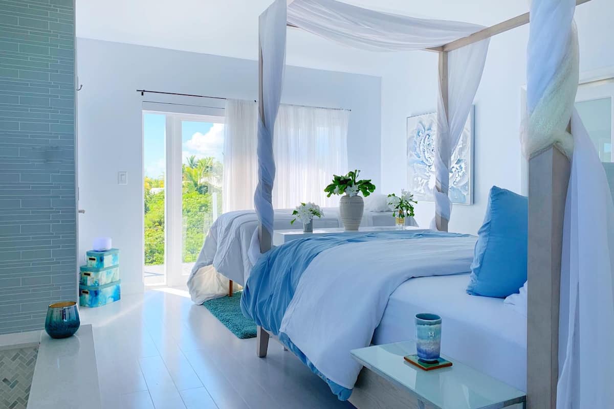 Ein Schlafzimmer mit einem Himmelbett, einem Nachttisch mit Glas und Blick ins Freie.