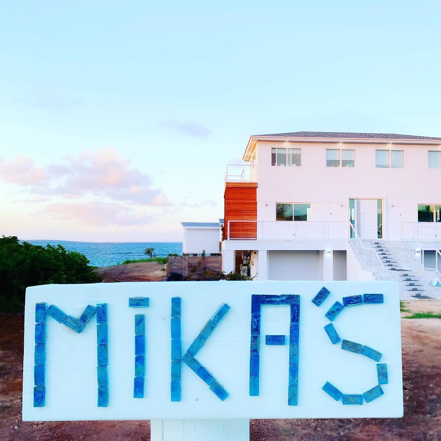 Egy modern, kétszintes ház, amelynek van egy erkélye, és egy „MIKA’S” feliratú tábla díszíti.