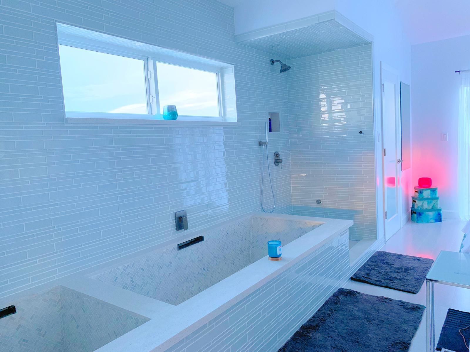 Ein modernes Badezimmer mit einer großen Badewanne, einem Fenster und einer Dusche.