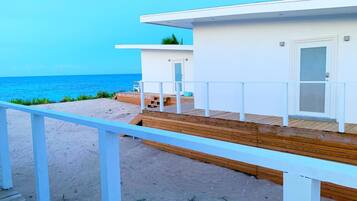 A beachside building with a wooden deck and a white railing, overlooking the ocean.