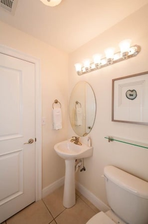 A bathroom with a white sink, a mirror, a toilet, and a glass shelf. - Cassine Station 30A by Panhandle Getaways (Santa Rosa Beach)