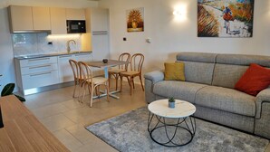 Une cuisine moderne avec des meubles blancs, un four à micro-ondes et un coin repas comprenant une table et des chaises.