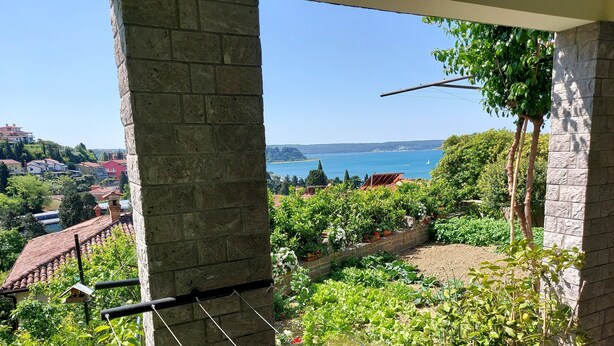 Un balcon donnant sur un jardin et un plan d’eau.