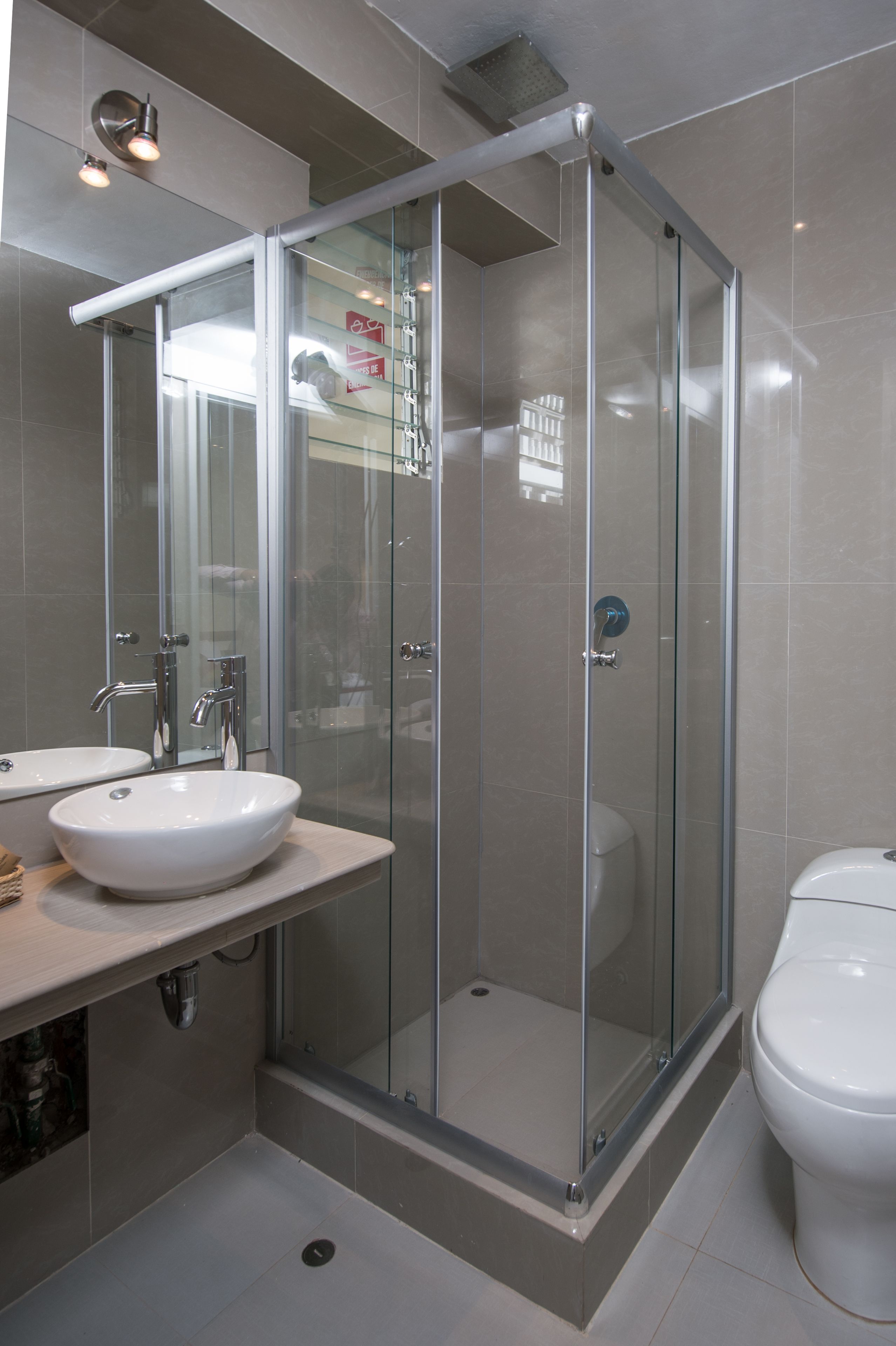 Une salle de bain moderne avec une douche à parois de verre, un lavabo blanc et des toilettes.
