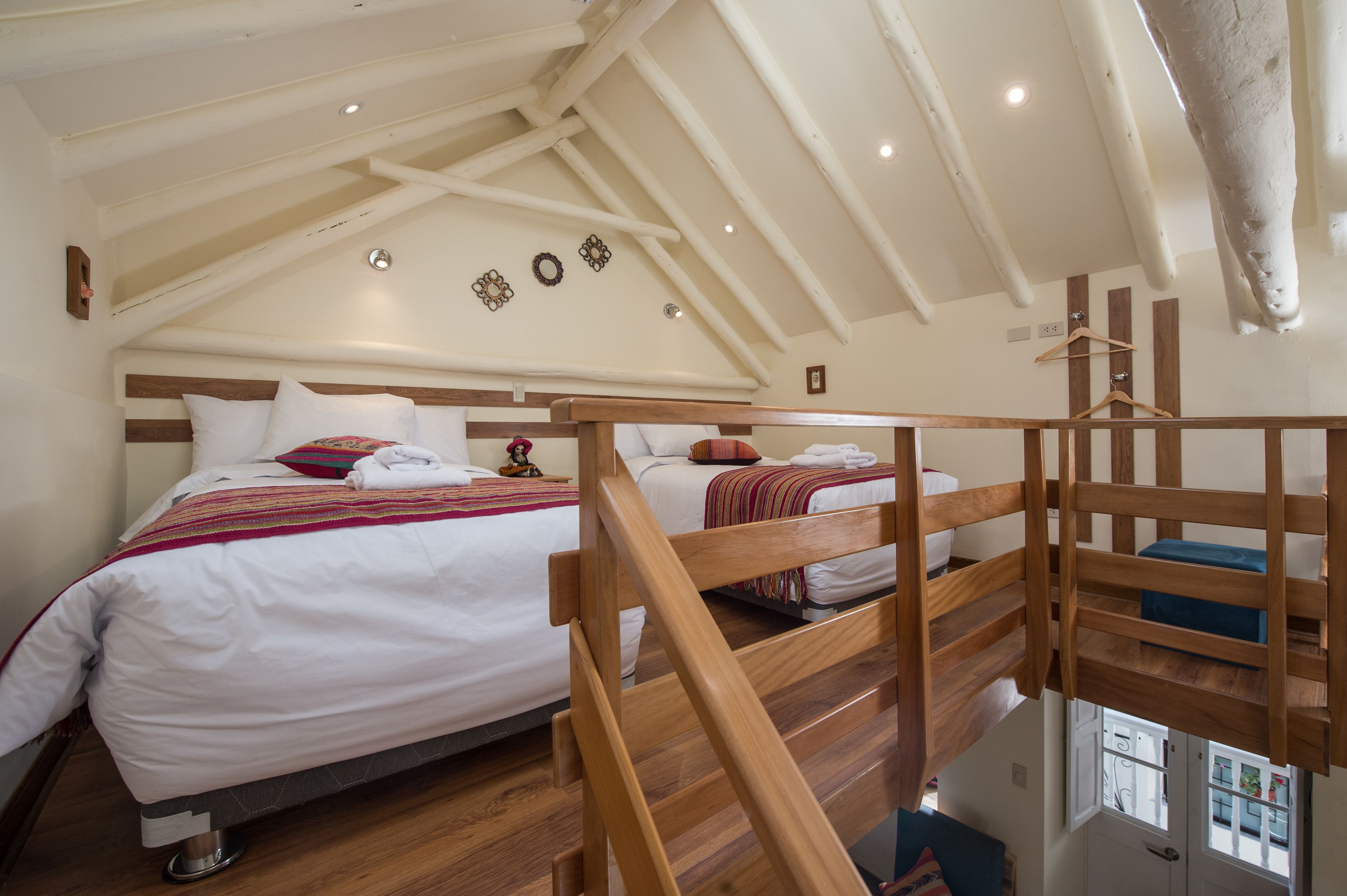 A bedroom with a sloped ceiling, wooden bunk beds, and a view of the outside through a window.