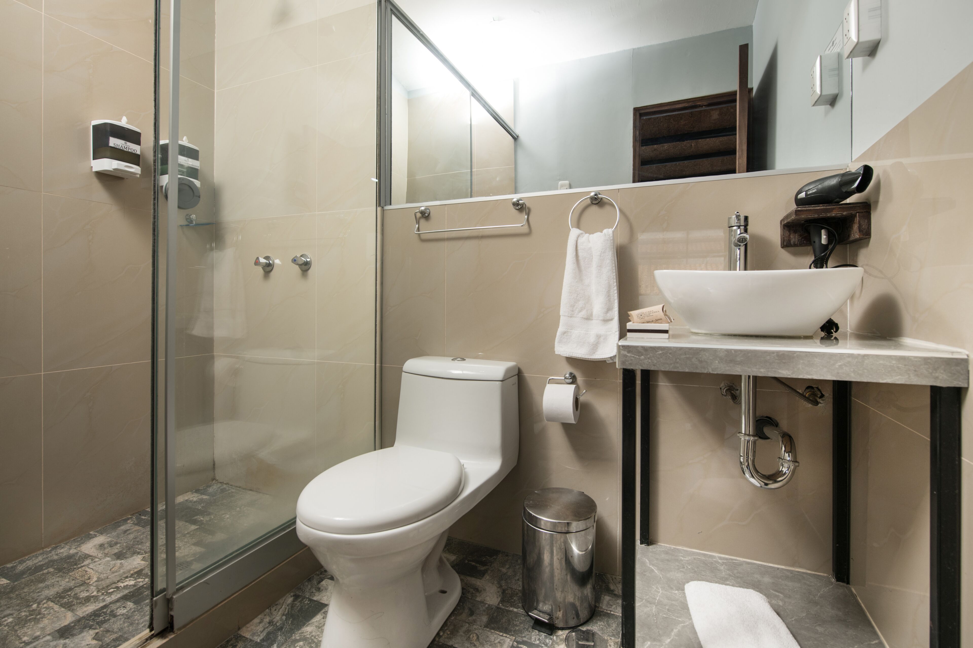 A modern bathroom with a glass shower enclosure, a toilet, a sink, and a trash can.