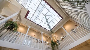 A multi-level atrium with white railings, a glass ceiling, and hanging plants. - Casa Cavassa Centro Histórico Cusco (Cusco)