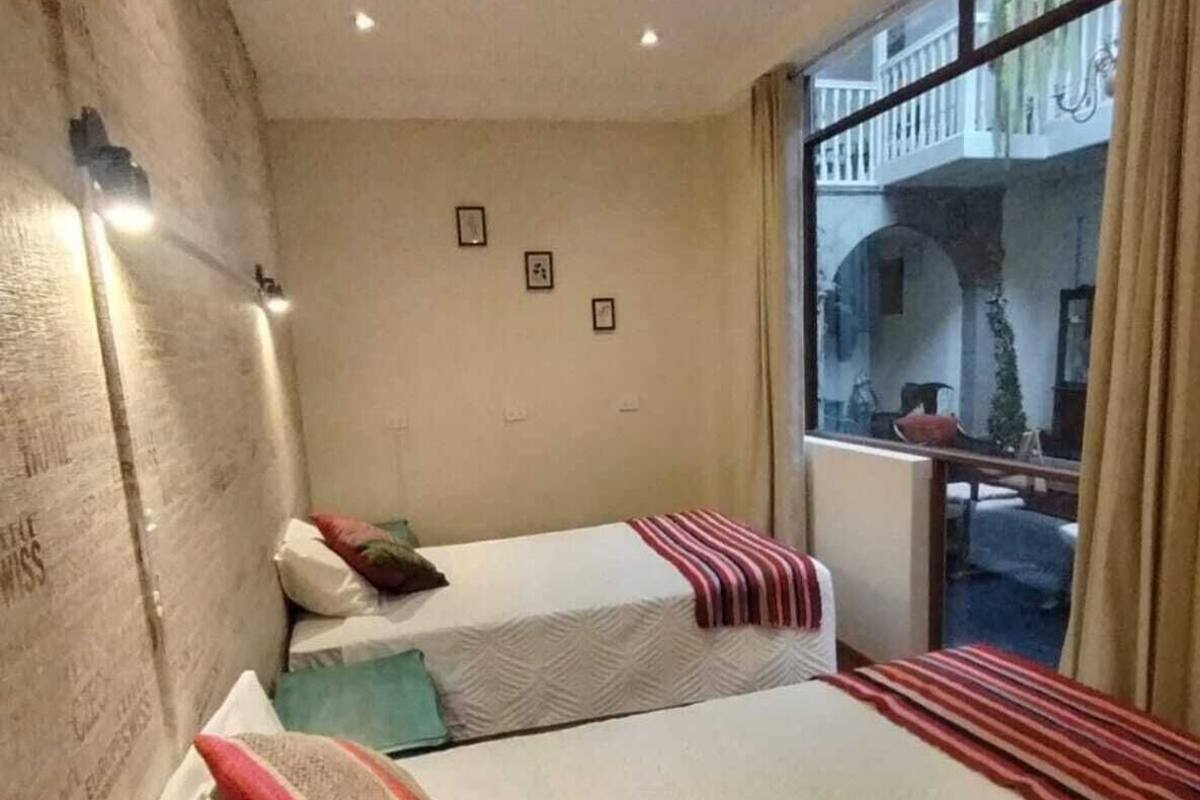 A hotel room with two beds, a balcony with a view, and a ceiling with recessed lighting.