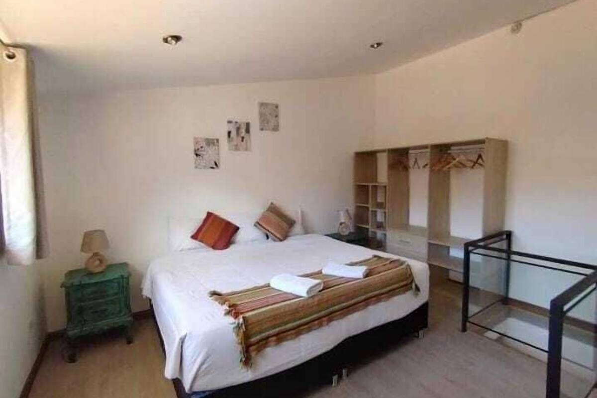 A bedroom with a bed, a nightstand, a dresser, and a mirror.