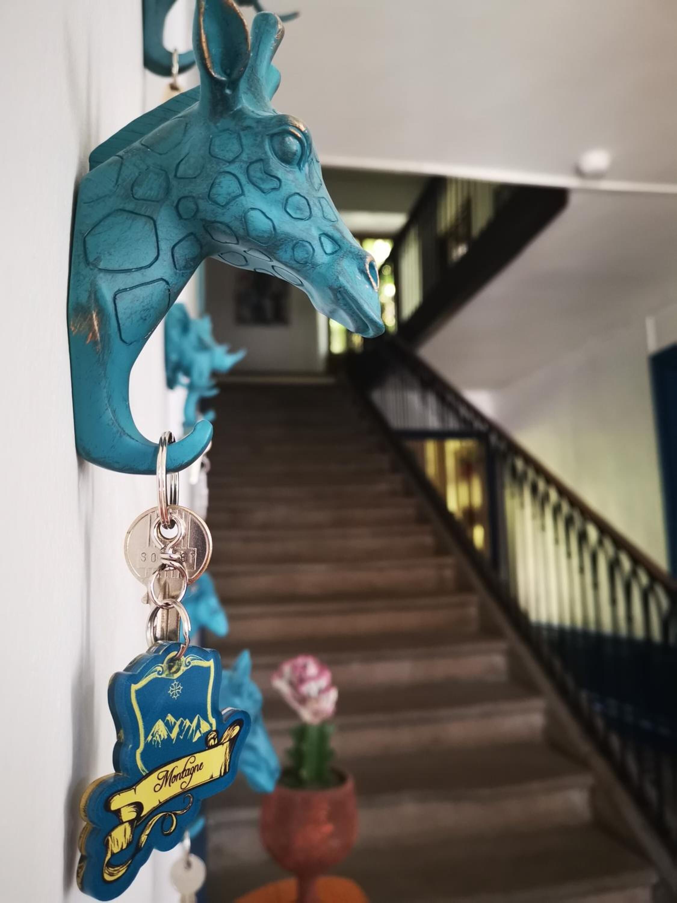 Una escala amb una decoració de cap de girafa blava i un clau penjat de disseny blau i groc.