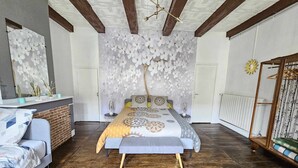 A bedroom with a large bed, a wooden floor, a mirror, and a wardrobe.