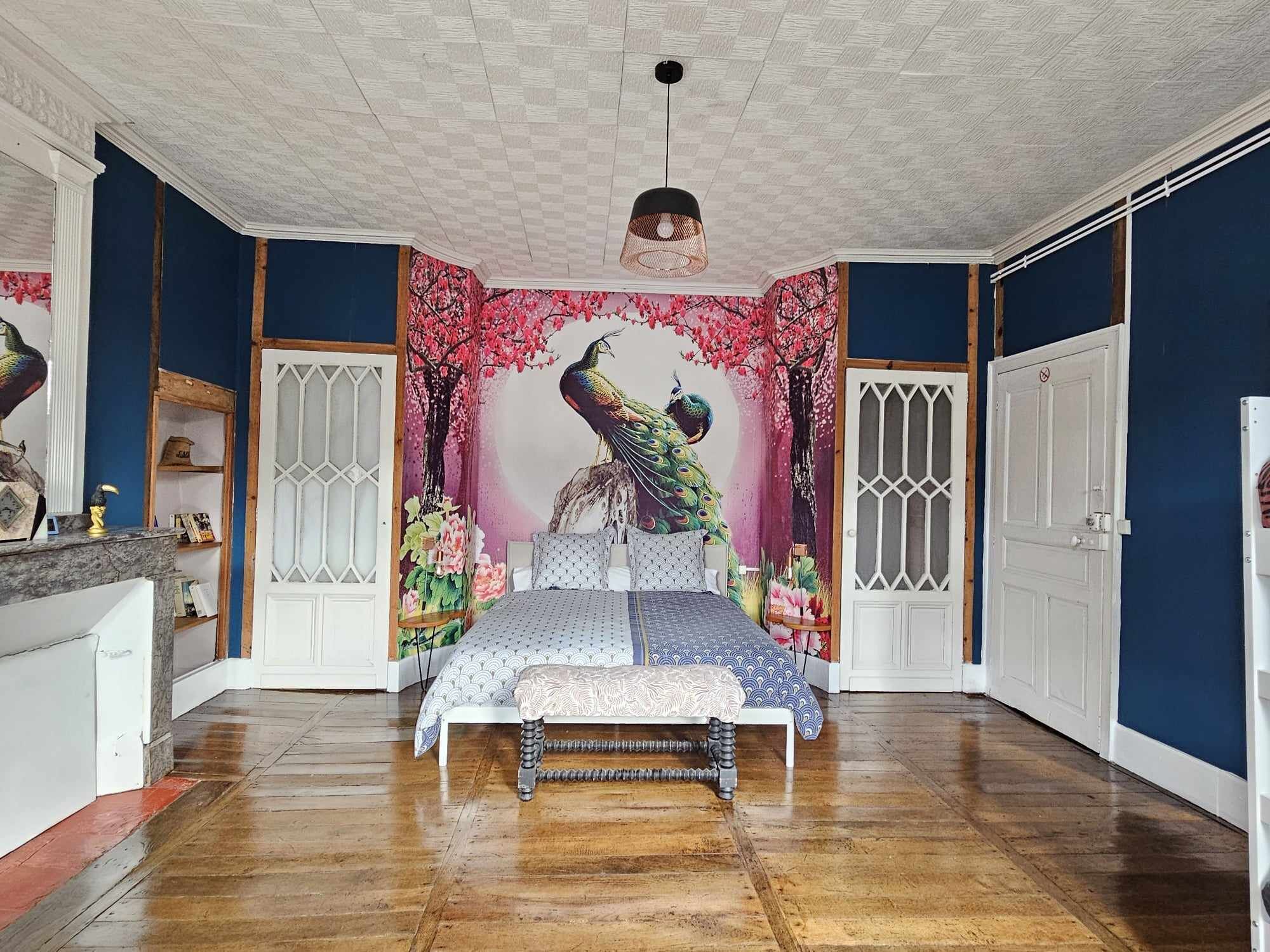 A bedroom with a bed, a decorative wall mural, and a ceiling fan.