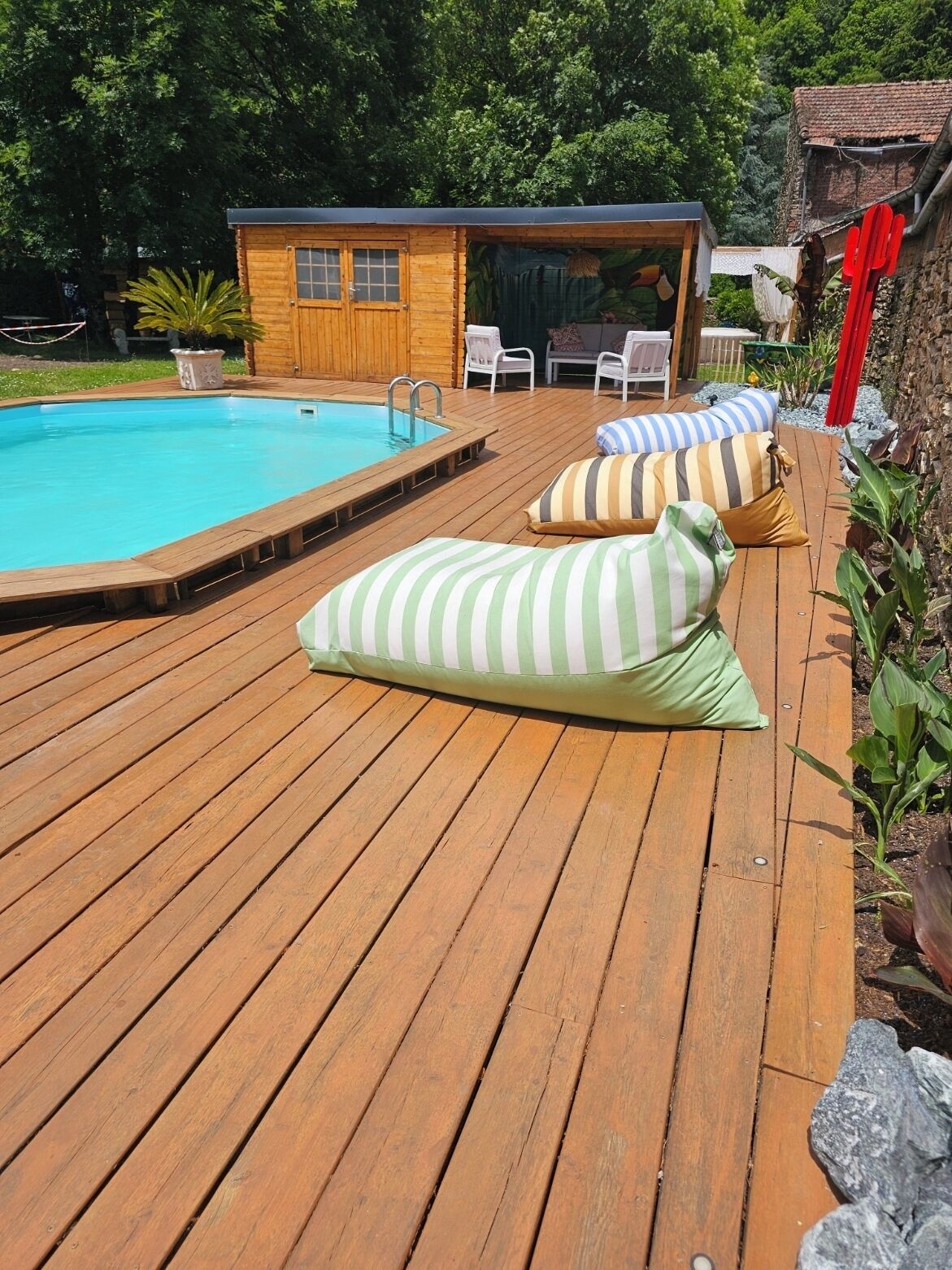 Une terrasse en bois avec une piscine, des chaises longues et un petit chalet en bois.
