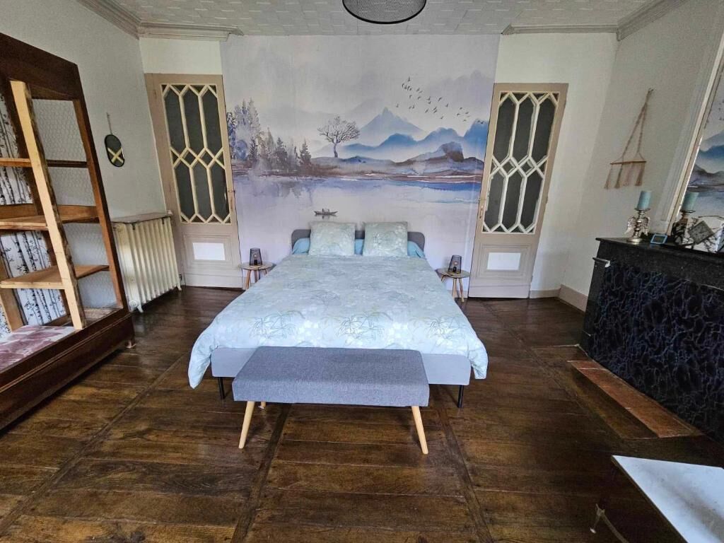 Un dormitorio con una cama grande, piso de madera, un mural en la pared y una estantería.