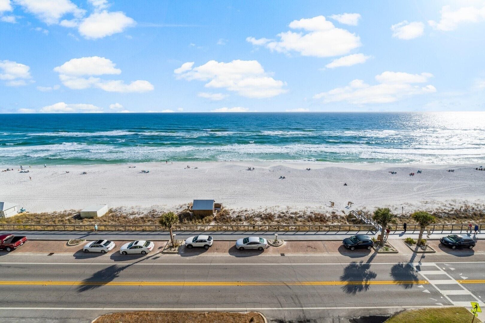A beach with a road in the foreground and a clear view of the ocean.