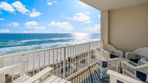 A balcony with wicker furniture overlooking a beach with waves and a clear sky. - Majestic Sun Beach Resort by Panhandle Getaways (Miramar Beach)