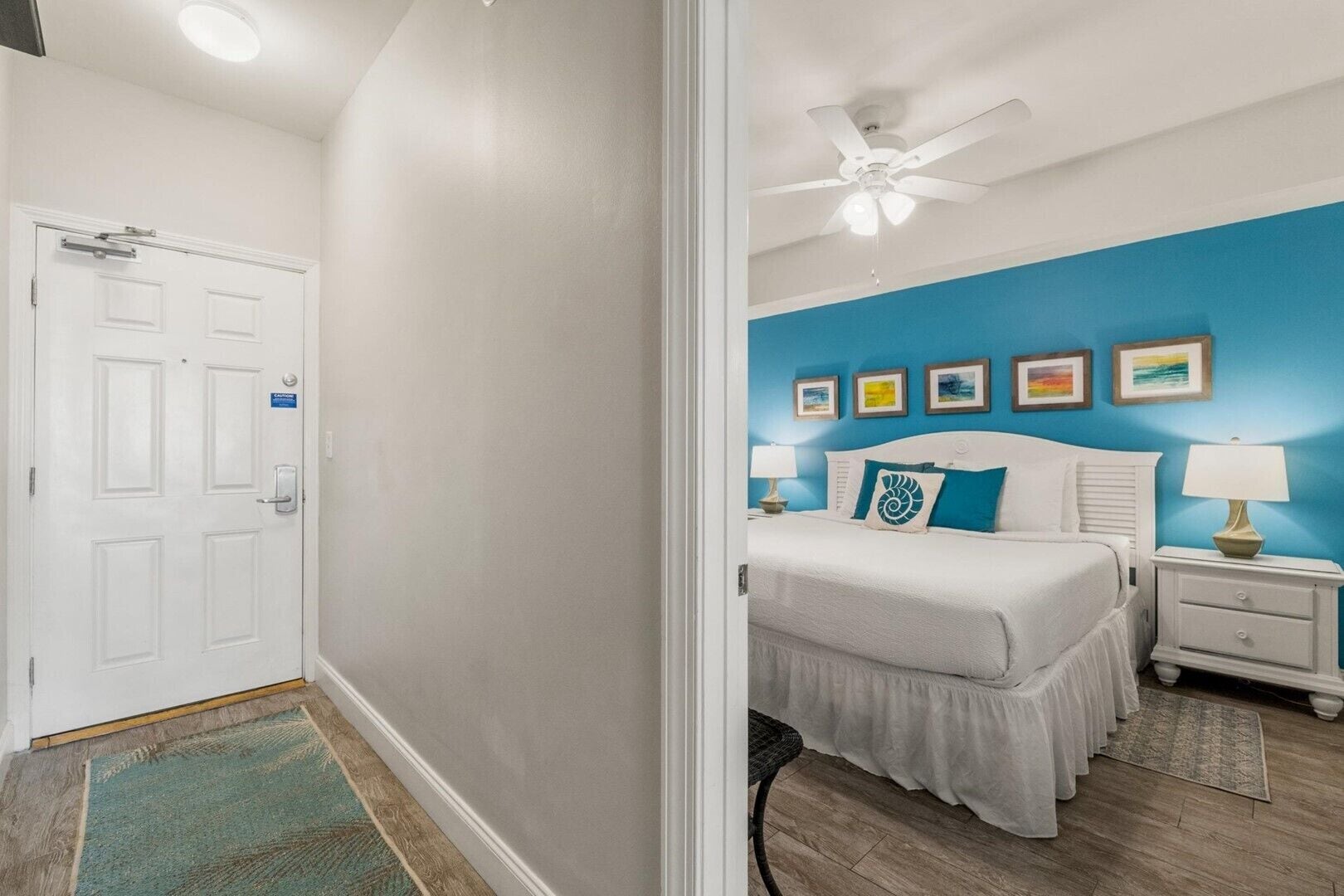 A bedroom with a bed, bedside tables, a ceiling fan, and a door.