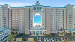 A large hotel with multiple floors, a central archway, and a view of the ocean. - Majestic Sun Beach Resort by Panhandle Getaways (Miramar Beach)