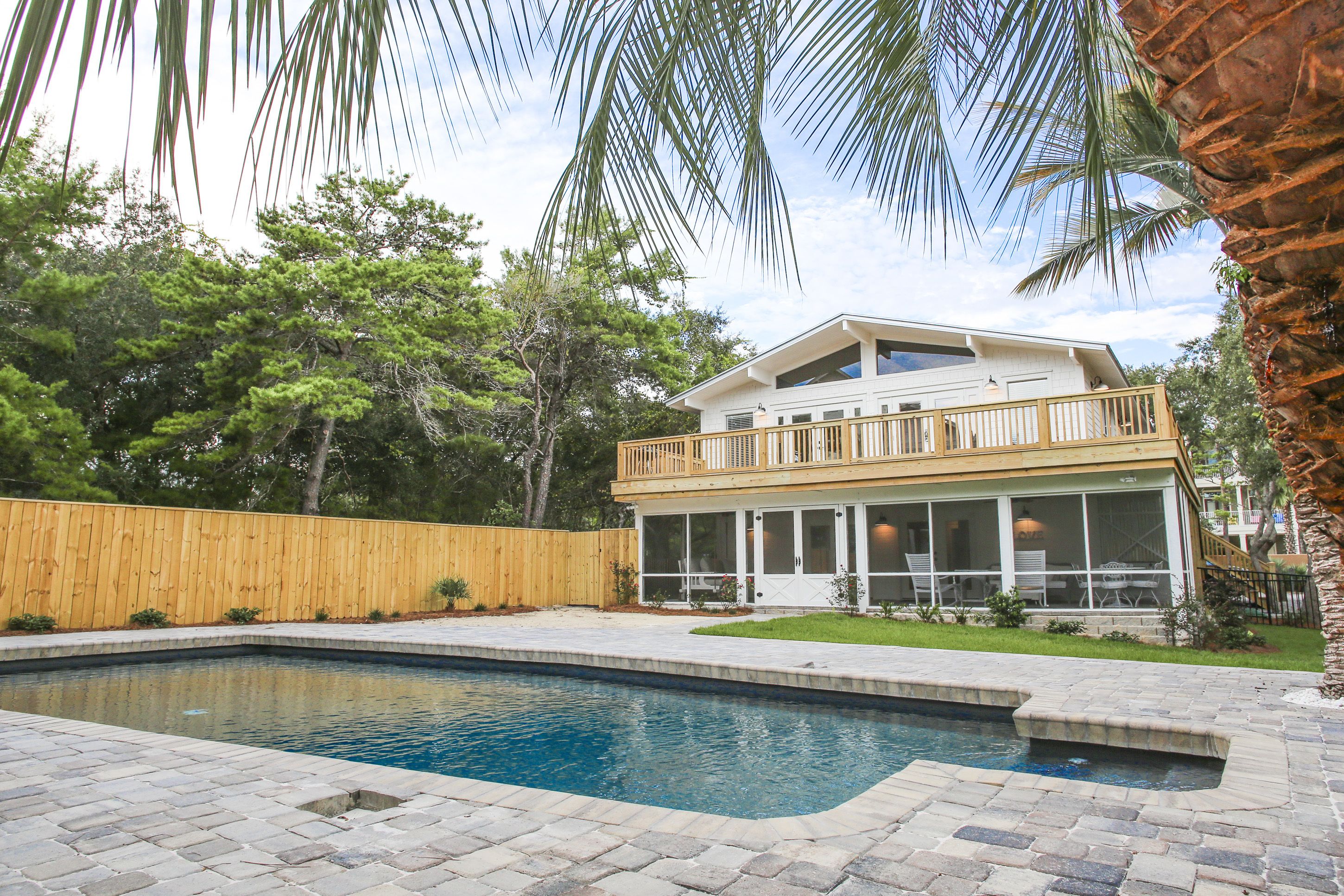 A two-story house with a large deck and a swimming pool.