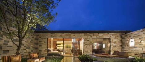 A modern outdoor patio with a stone wall, seating area, and a water feature.
