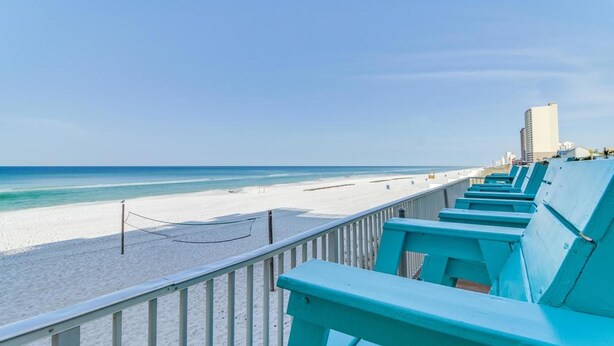 A beach view with a row of turquoise chairs and a white railing. - Fontainebleau Terrace by Panhandle Getaways (Panama City Beach)
