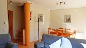 Ein Wohnzimmer mit einer Couch, einem Esstisch mit Stühlen und einer Treppe.