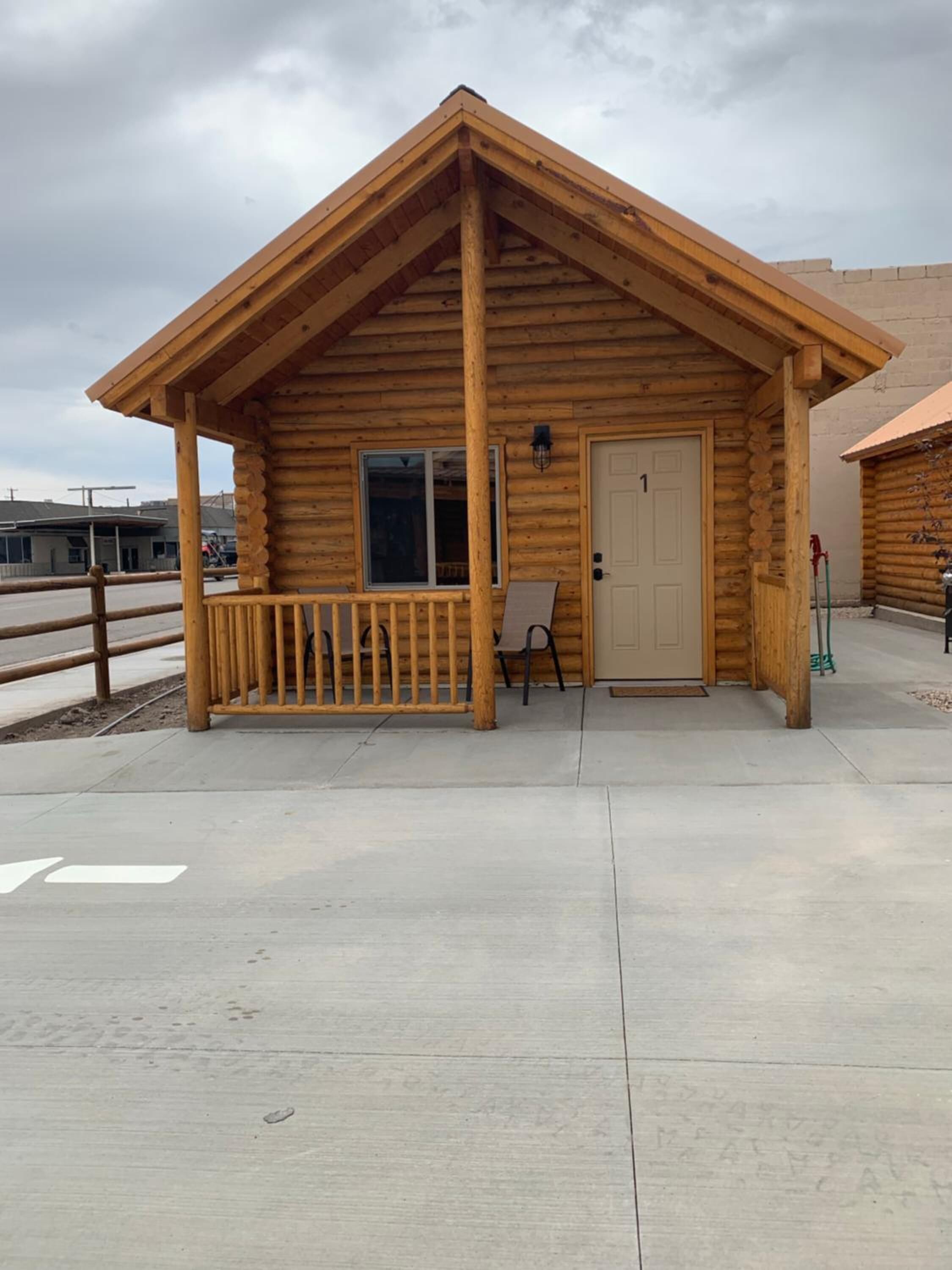 Une cabane en rondins avec une véranda, une porte et une fenêtre.