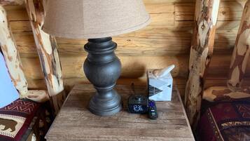 A wooden nightstand with a lamp, a box of tissues, and a remote control.